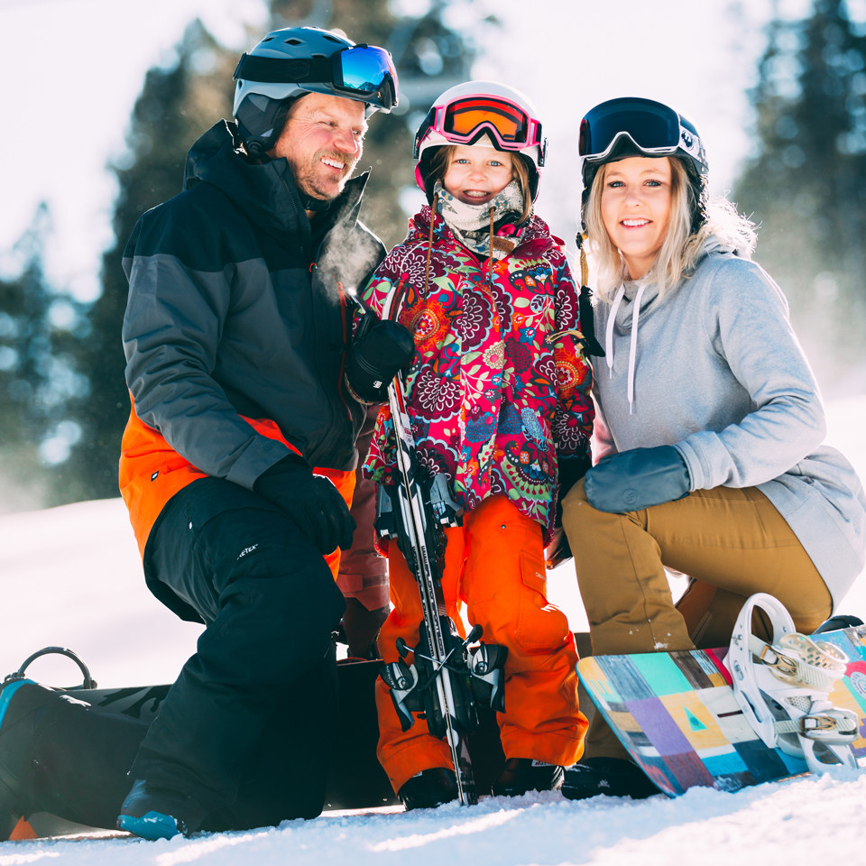 family with ski and snowboard equipment